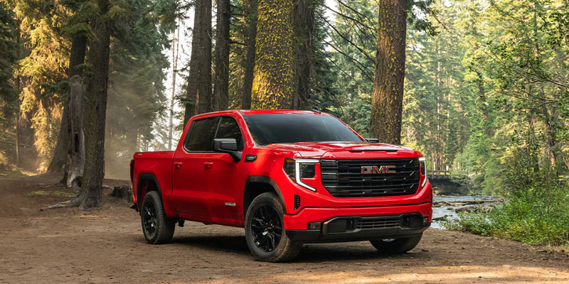 A red GMC truck parked in a forest.