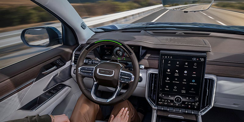 Image of a man using hands-free-driver-assistance while in a GMC Acadia driving on a highway