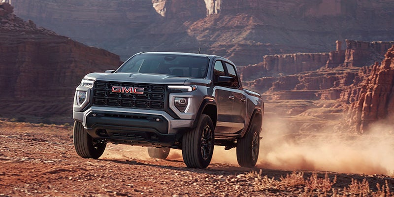 2024 GMC Canyon AT4X driving on a dirt road with a canyon in the background