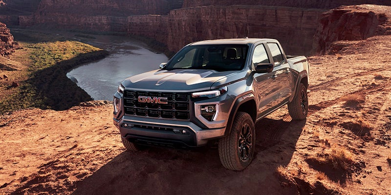 2024 GMC Canyon AT4X on a dirt road with a canyon and a body of water in the background