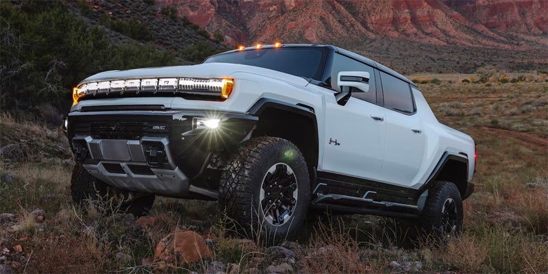 2024 GMC Hummer EV with it's front wheels propped up on a rock