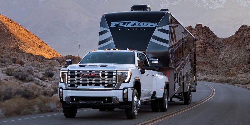 2024 GMC Sierra 2500HD driving on a highway with a trailer