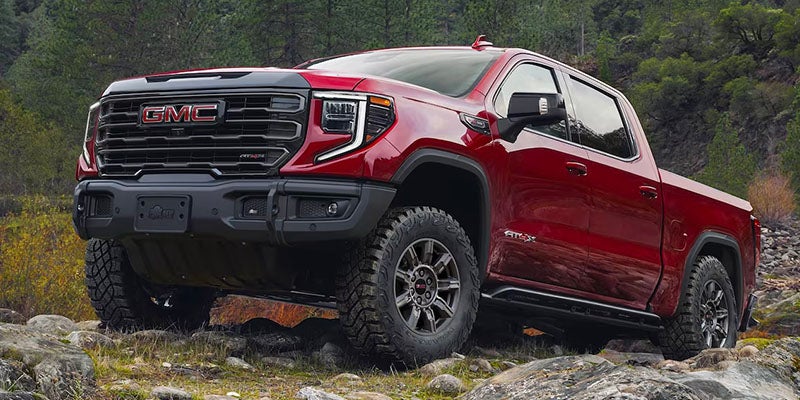 A red 2025 GMC Sierra 1500 at an angle going up a rocky road